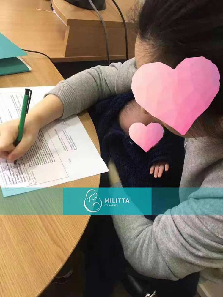 孩子出生证已经拿到-夫妻俩一人抱着一个孩子签写相关文件